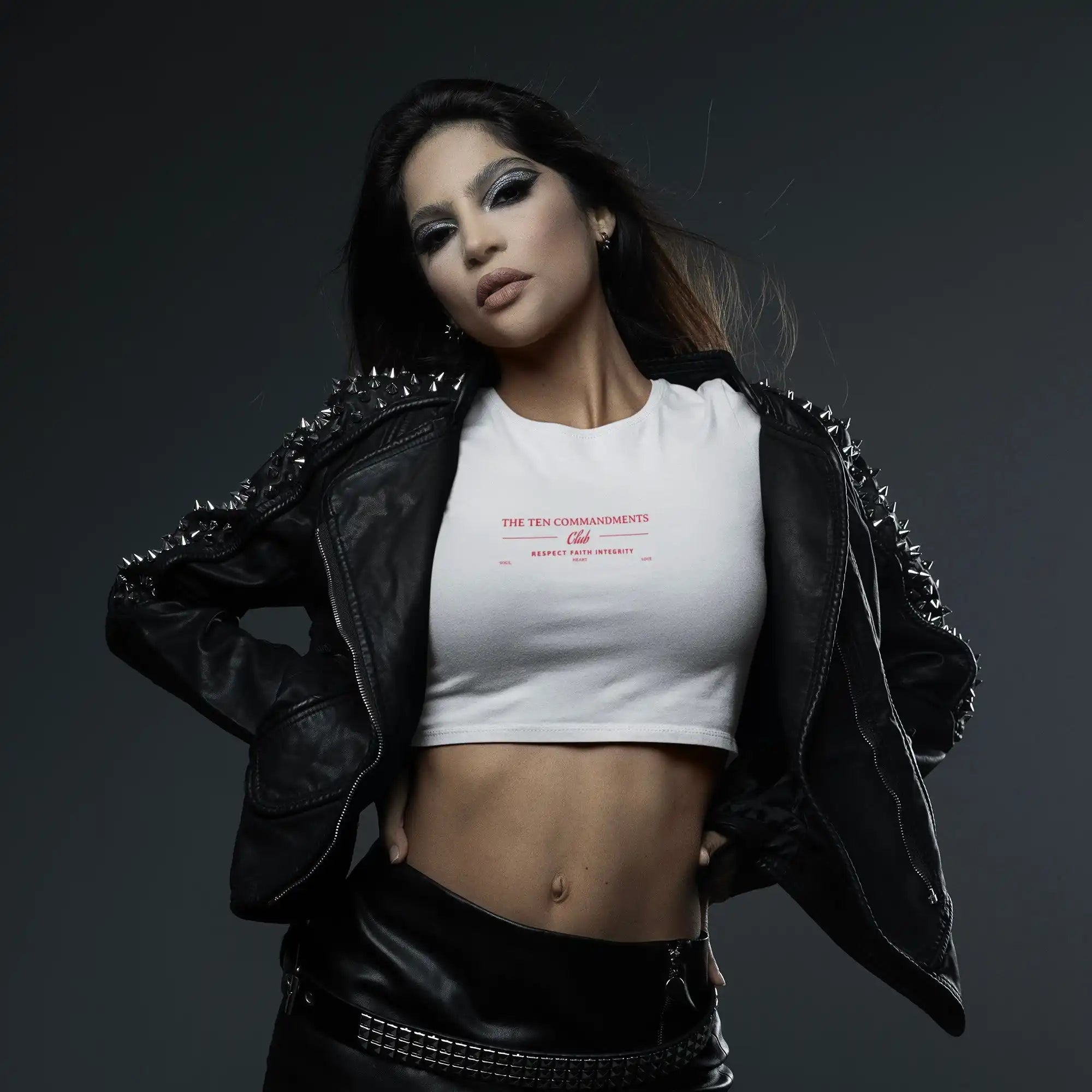 A person wearing a white crop top and black leather jacket with studs.