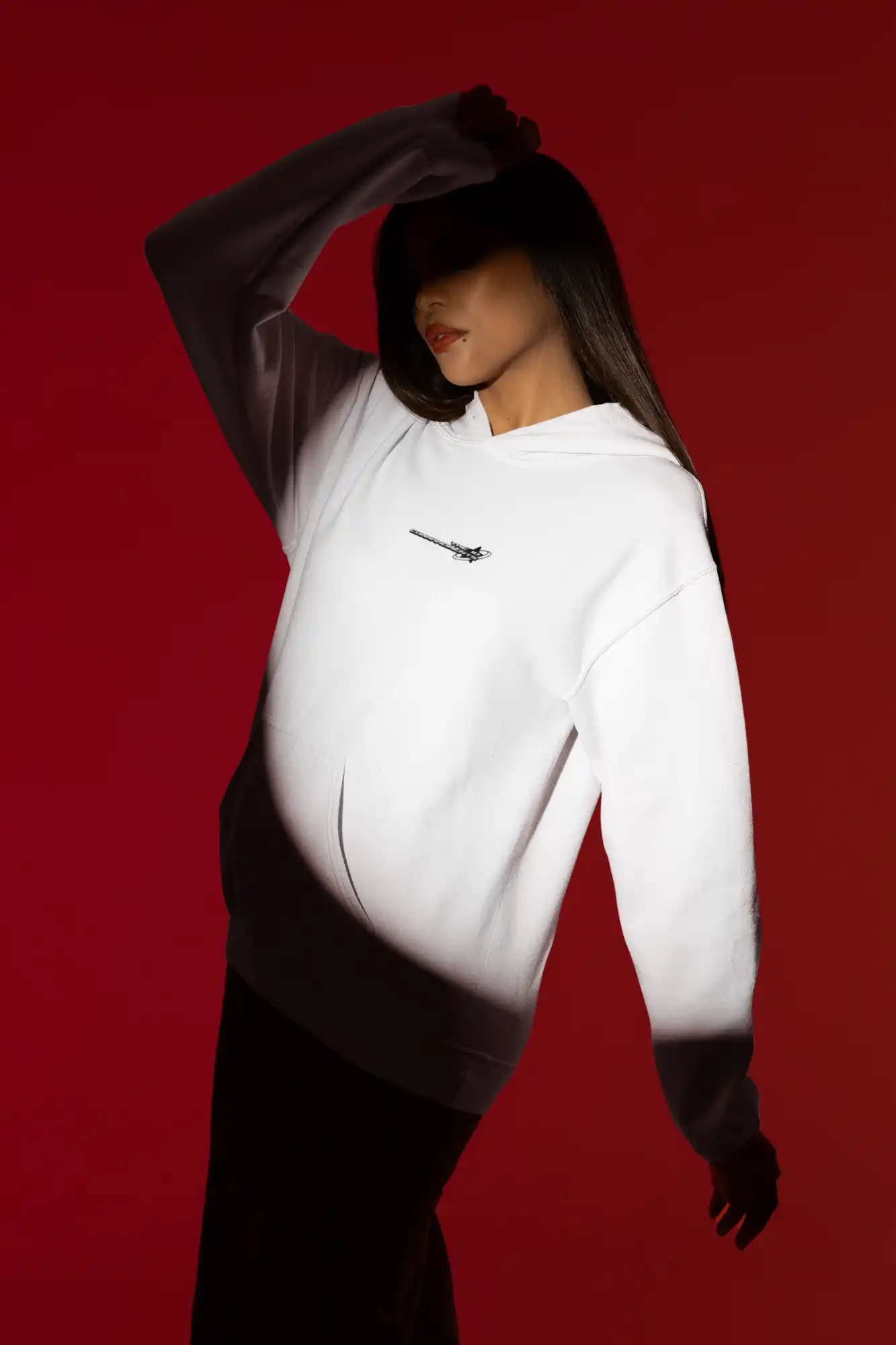 White Nike sweatshirt worn in a dramatic pose against shadows.